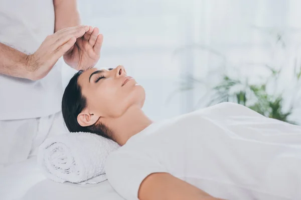 Cropped shot of calm young woman with closed eyes receiving reiki therapy — Stock Photo