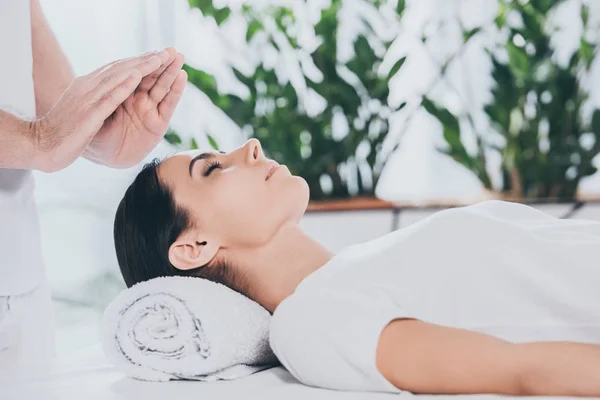 Cropped shot of calm young woman with closed eyes receiving reiki treatment — Stock Photo