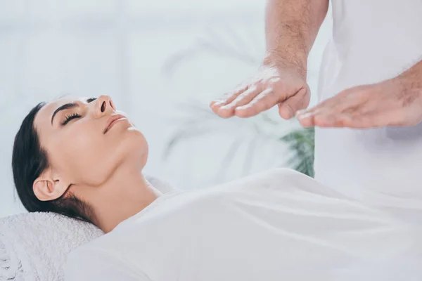 Abgeschnittene Aufnahme einer jungen Frau mit geschlossenen Augen, die eine Reiki-Behandlung erhält — Stockfoto