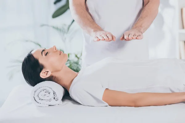 Tiro recortado de mujer joven con los ojos cerrados que reciben tratamiento reiki — Stock Photo