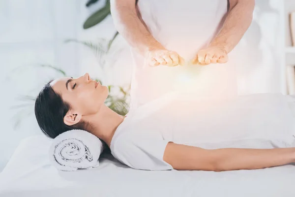 Tiro recortado de mujer joven que recibe tratamiento de reiki por encima del pecho - foto de stock