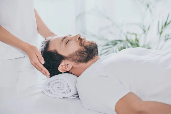 Cropped shot of man with closed eyes receiving reiki treatment — Stock Photo