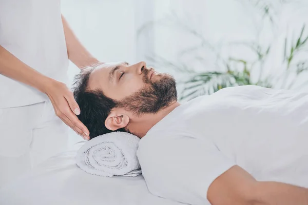 Recortado disparo de hombre con los ojos cerrados recibir tratamiento reiki - foto de stock