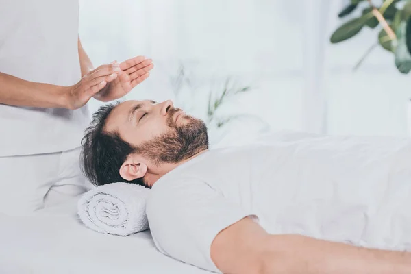 Tiro cortado de homem barbudo calmo recebendo sessão de cura reiki — Fotografia de Stock