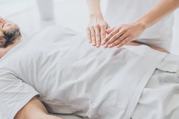Cropped shot of bearded man receiving reiki treatment on stomach — Stock Photo