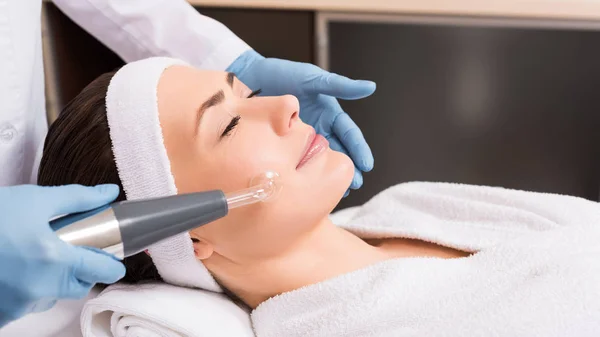 Beautician making darsonvalization to woman at beauty salon — Stock Photo