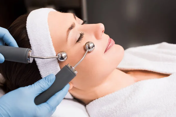 Esthéticienne faisant massage levant sur le visage de la femme au salon de beauté — Photo de stock