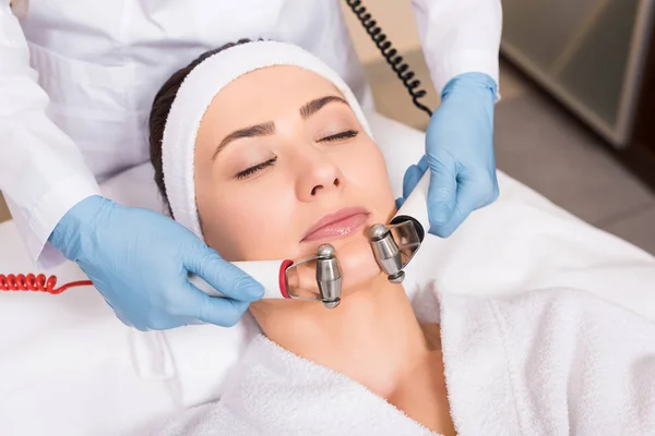 Косметолог робить масаж обличчя з обладнанням для жінки в салоні краси — стокове фото