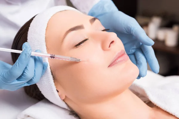 Esteticista haciendo inyección cara atractiva mujer en salón de belleza - foto de stock