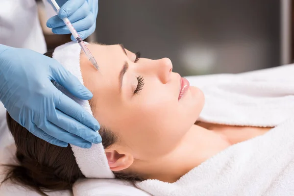 Esteticista haciendo inyección a la mujer en la cara en el salón de belleza - foto de stock