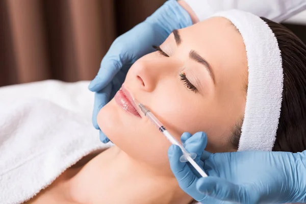 Cosmetologist doing injection on woman lip at beauty salon — Stock Photo