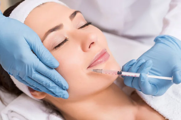 Cosmetólogo haciendo inyección en la cara a la mujer en el salón de belleza - foto de stock