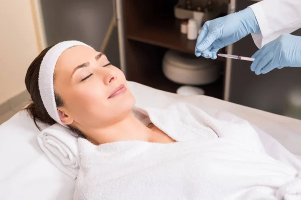 Beautician holding syringe in front of woman face at beauty salon — Stock Photo