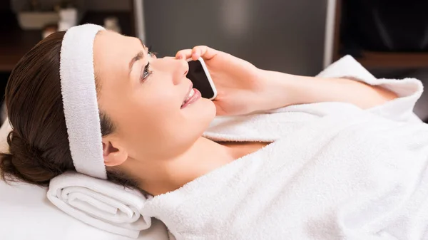 Attractive woman lying and talking on smartphone at beauty salon — Stock Photo
