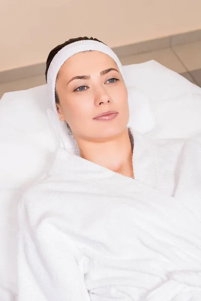 Woman lying in white bathrobe and hairband at beauty salon — Stock Photo