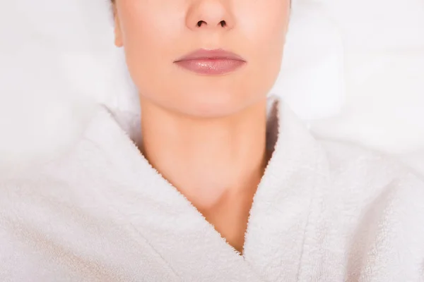 Обрезанный вид женщины, лежащей в белом халате в салоне красоты — стоковое фото