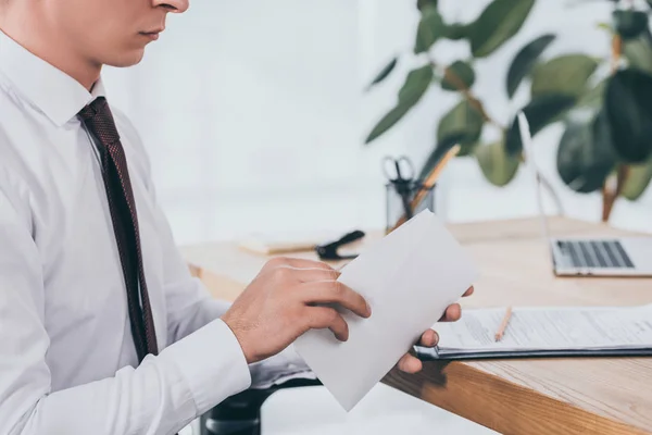 Visão cortada de empresário abrindo envelope no escritório, conceito de compensação — Fotografia de Stock