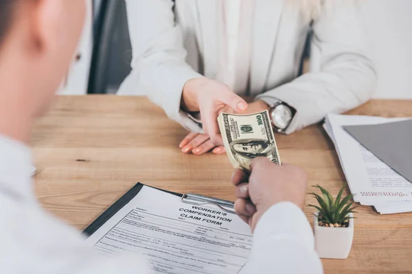 Partial view of businessman holding money with woman at workplace, compensation concept — Stock Photo