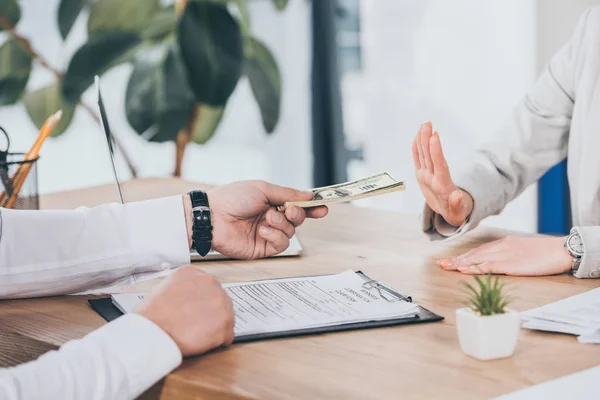 Vista recortada de hombre de negocios dando dinero mientras que la mujer se niega, concepto de compensación - foto de stock