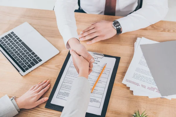 Visión parcial del empresario estrechando la mano de la mujer en el lugar de trabajo, concepto de compensación - foto de stock