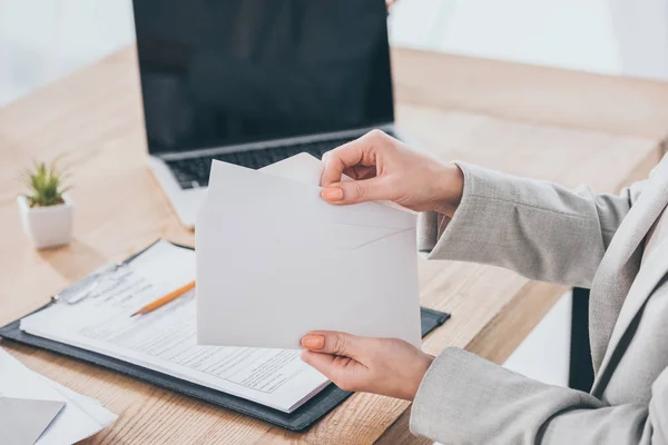 Cropped view of businesswoman holding envelope at workplace, compensation concept — Stock Photo