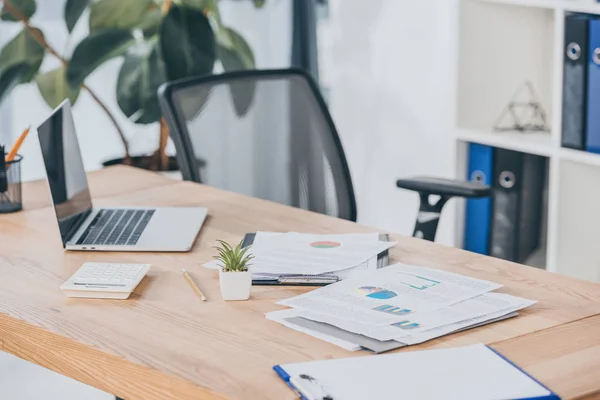 Selective focus of table with laptop, documents, chairs in office — Stock Photo