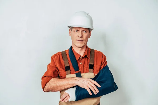 Reparador con vendaje de pie y brazo de sujeción sobre fondo blanco - foto de stock