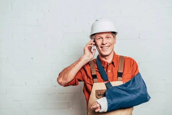 Reparateur mit Armverband spricht auf Smartphone vor weißem Hintergrund — Stockfoto
