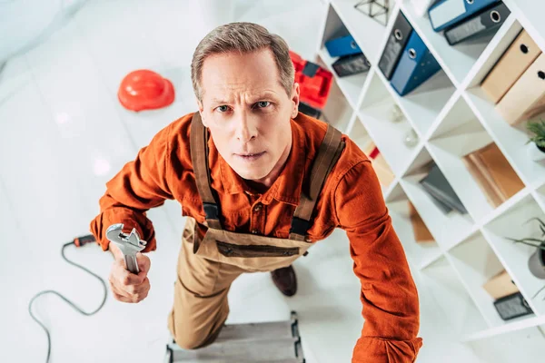 Top view of man climbing on ladder with wrench in office — Stock Photo