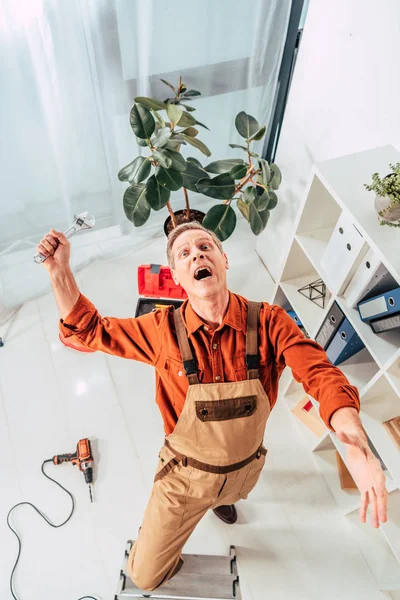 Repairman falling from ladder with wrench in hand in office — Stock Photo