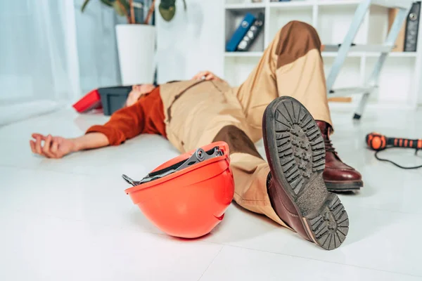 Réparateur couché sur le sol blanc en uniforme dans le bureau — Photo de stock