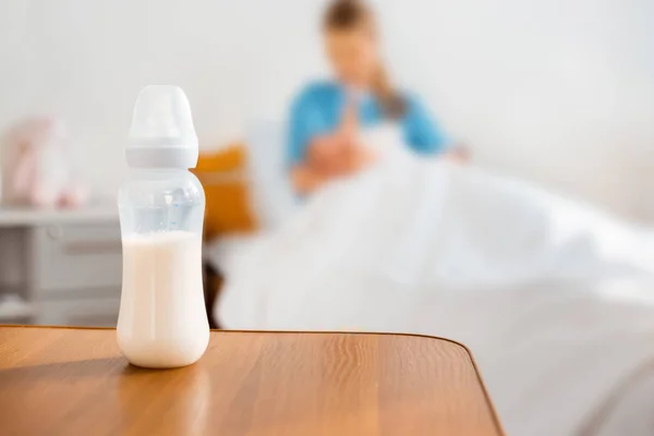 Nahaufnahme einer Babyflasche mit Milch und einer stillenden Mutter im Krankenhauszimmer — Stockfoto
