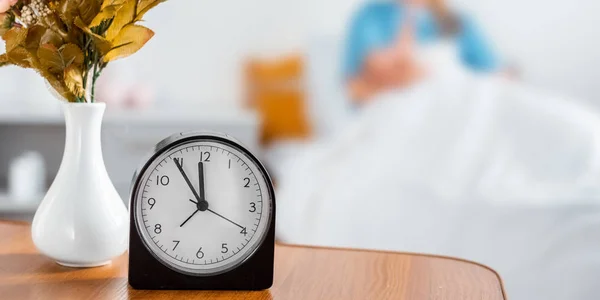 Close-up view of clock, flowers in vase and mother with newborn baby behind in hospital room — Stock Photo