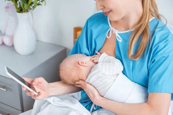 Tiro recortado de bebê de amamentação mãe sorridente e usando smartphone no quarto do hospital — Fotografia de Stock