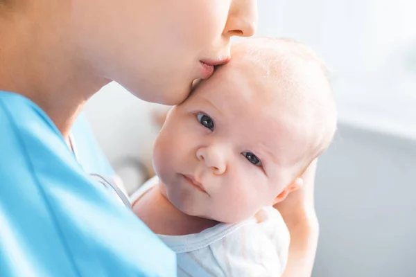 Plan recadré de jeune mère embrassant adorable bébé regardant la caméra — Photo de stock