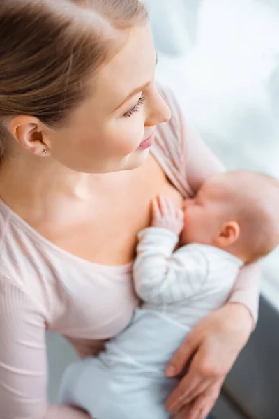 Vue grand angle de la jeune mère souriante qui allaite bébé à la maison — Photo de stock