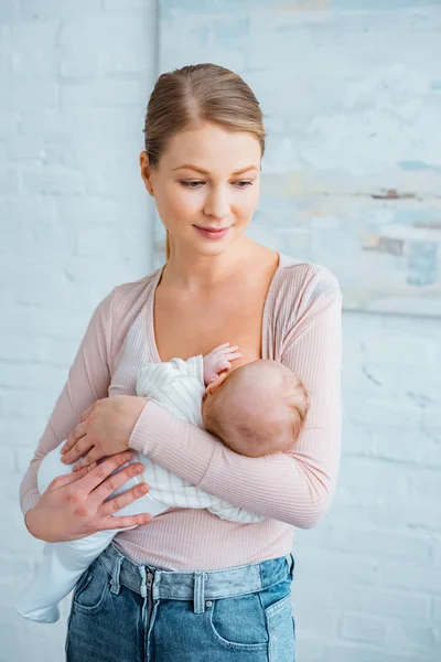 Lächelnde junge Mutter steht und stillt Baby zu Hause — Stockfoto