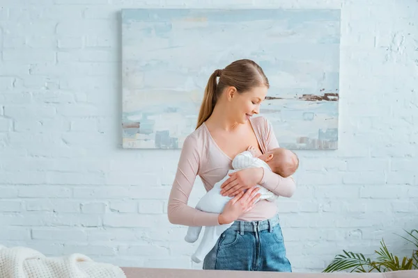 Schöne glückliche junge Mutter, die ihr Neugeborenes zu Hause stillt — Stockfoto