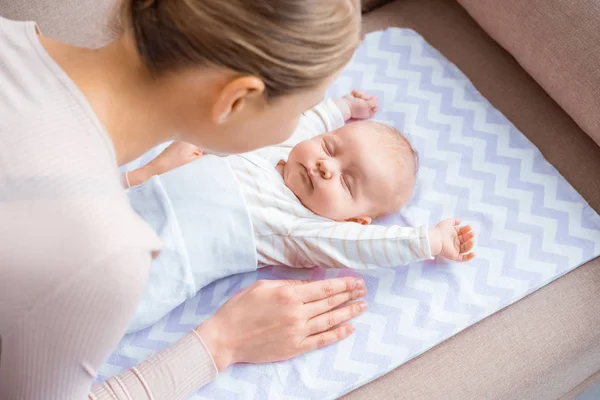 High angle view of young mother looking at adorable infant baby lying on sofa — Stock Photo