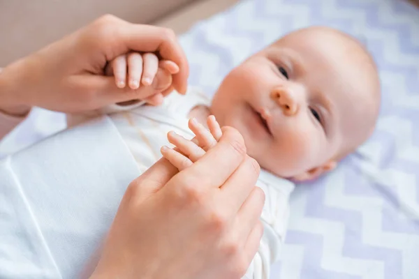 Schnappschuss einer Mutter, die Hände eines entzückenden Säuglings hält und in die Kamera schaut — Stockfoto