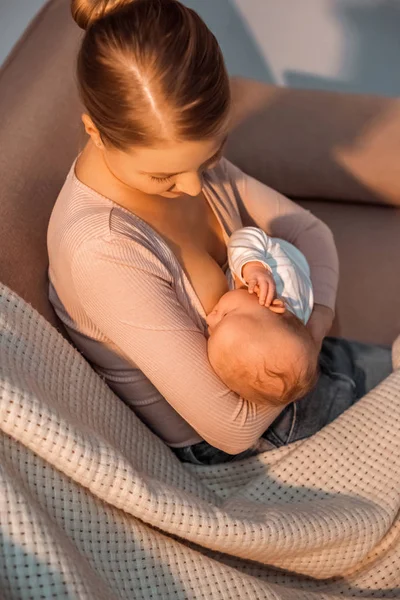 High angle view of young mother breastfeeding baby at night — Stock Photo