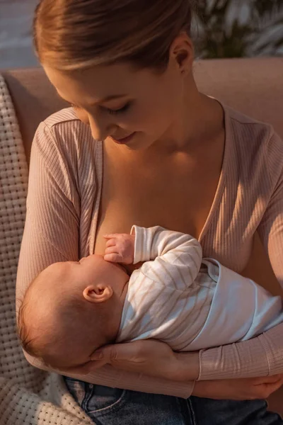 Bella sorridente giovane madre che allatta il bambino di notte — Foto stock