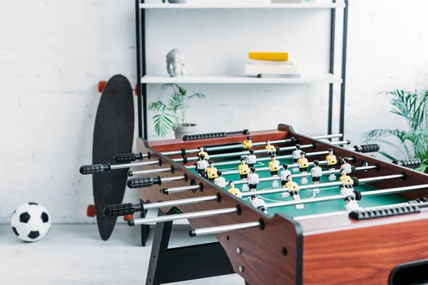 Football table with shelving rack, longboard and soccer ball on background — Stock Photo