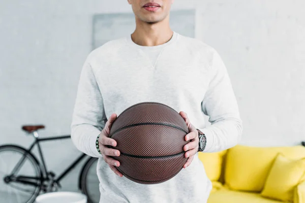 Partial view of man in white sweatshirt holding brown ball — Stock Photo