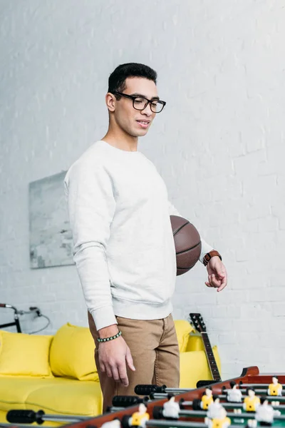 Junger gemischter Mann in weißem Sweatshirt steht am Fußballtisch — Stockfoto