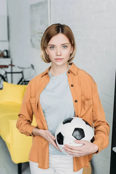 Bella giovane donna in camicia arancione con palla da calcio in mano — Foto stock