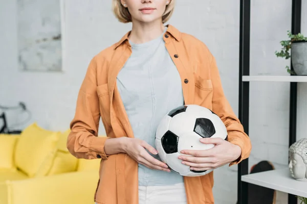 Vista parcial de la mujer en camisa naranja sosteniendo pelota de fútbol - foto de stock