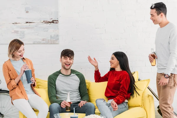Lachende multiethnische Freunde plaudern auf gelbem Tisch im Wohnzimmer — Stockfoto
