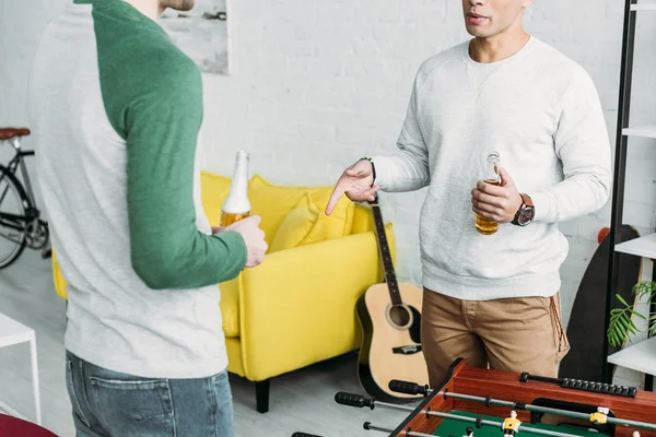 Partial view of men standing in living room and holding bottles of beer — Stock Photo