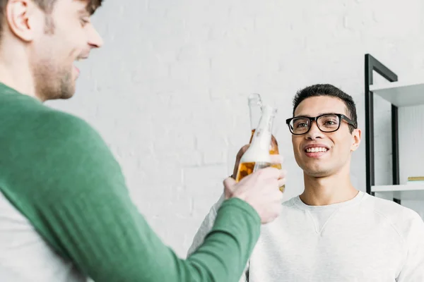 Glücklich lächelnde multikulturelle Freunde, die mit Bierflaschen klappern — Stockfoto